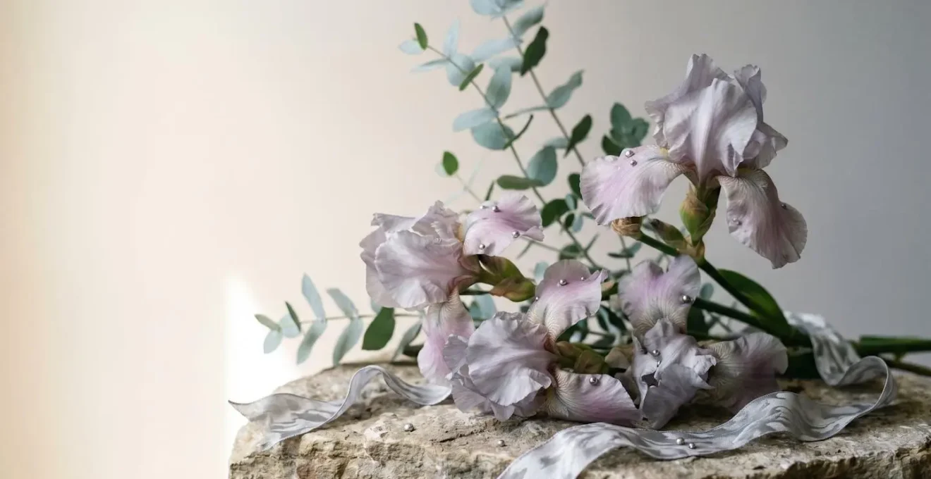 Elegant silver iris arrangement celebrating twenty-five years of marriage with dramatic lighting and negative space